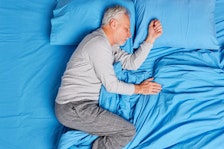 A man sleeps on blue sheets